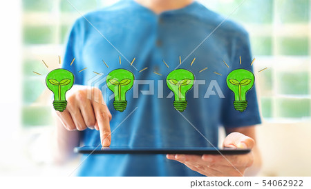 Eco light bulbs with man using a tablet 54062922