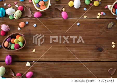 chocolate eggs and candy drops on wooden table 54064231