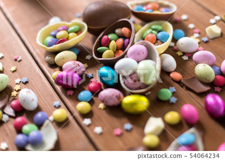 chocolate eggs and candy drops on wooden table chocolate eggs and candy drops on wooden table 54064234