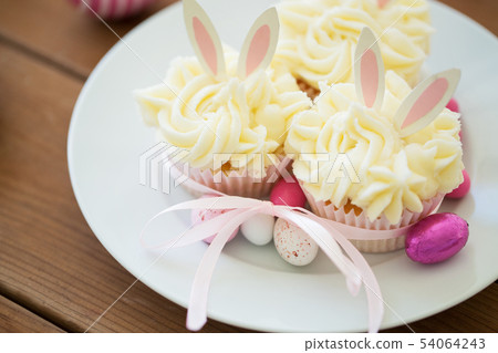 cupcakes with easter eggs and candies on table 54064243