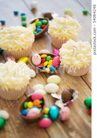 cupcakes with chocolate eggs and candies on table 54064248