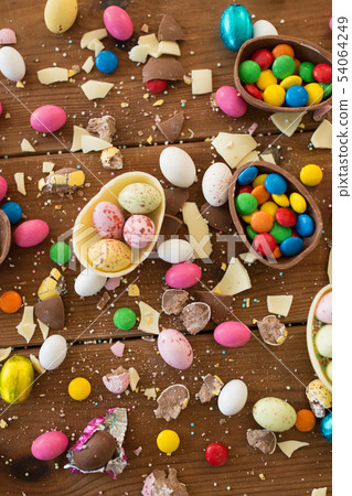 chocolate eggs and candy drops on wooden table 54064249
