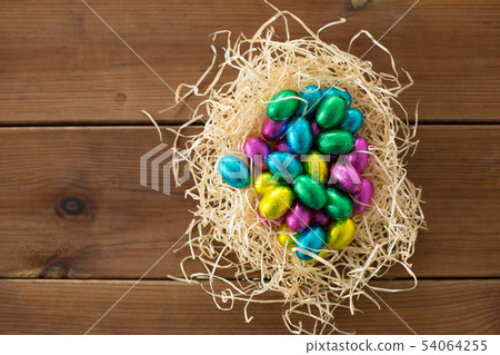 chocolate eggs in foil wrappers in straw nest chocolate eggs in foil wrappers in straw nest 54064255