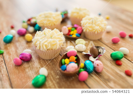cupcakes with chocolate eggs and candies on table 54064321