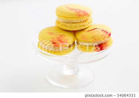 lemon yellow macarons on glass confectionery stand 54064331