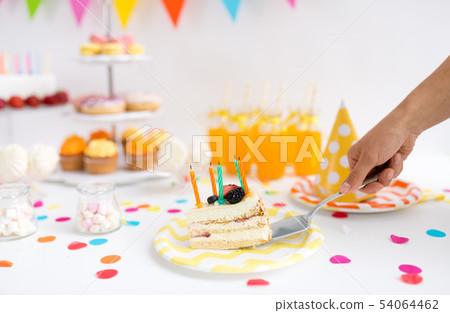 hand putting piece of birthday cake on plate 54064462