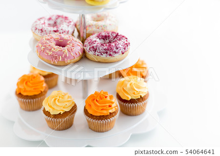 glazed donuts, cupcakes with frosting on stand glazed donuts, cupcakes with frosting on stand 54064641