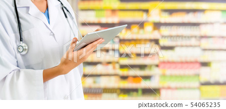 Pharmacist using tablet computer at pharmacy. 54065235
