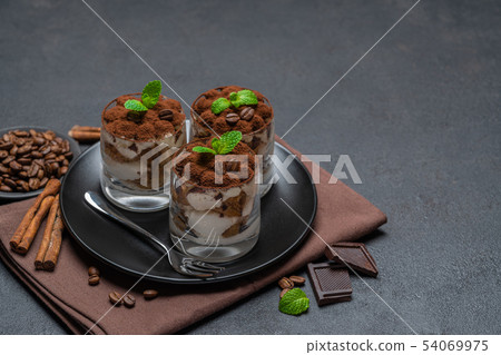 Classic tiramisu dessert in a glass on dark concrete background 54069975