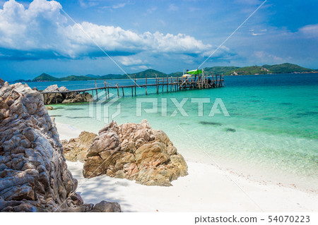 Wood bridge on the beach with water and blue sky. 54070223