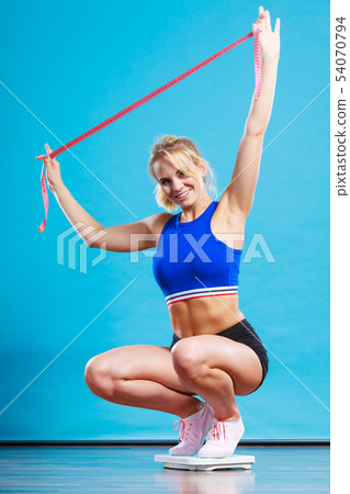 Joyful girl standing on bathroom scales 54070794
