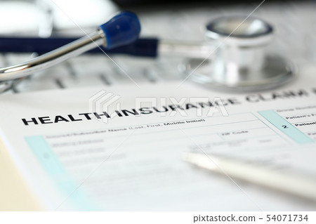 Stethoscope head and silver pen lying on application form 54071734