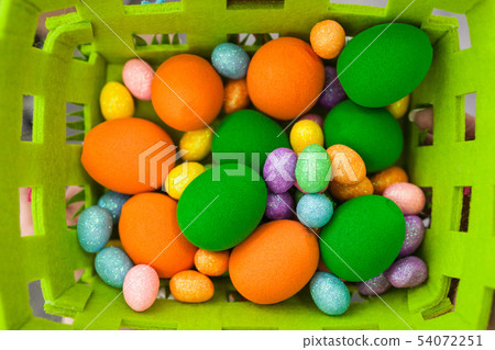 Easter colorful eggs of different sizes in a basket Easter colorful eggs of different sizes in a basket 54072251