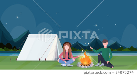 couple hikers roasting marshmallow candies on campfire hiking camping concept man women travelers on 54073274