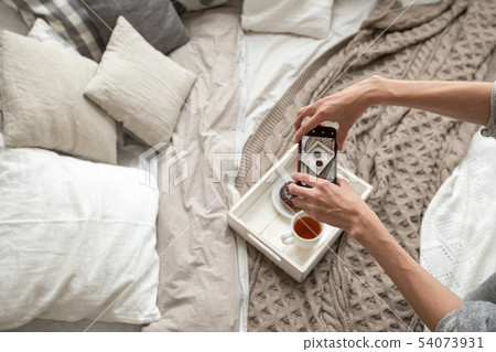 Woman taking shot of tray with food on bed Woman taking shot of tray with food on bed 54073931