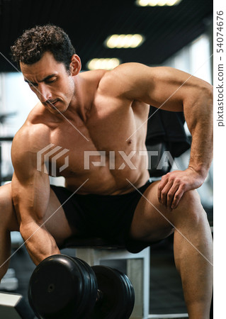 bodybuilder execute exercise with dumbbells 54074676
