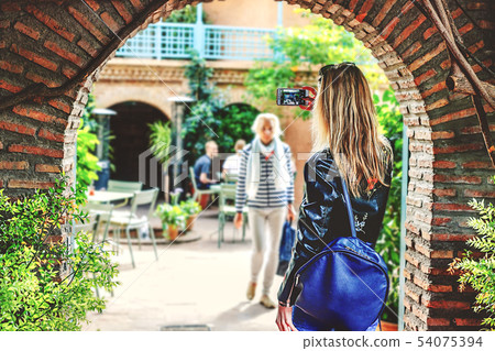 A girl with blond hair takes pictures of the A girl with blond hair takes pictures of the 54075394