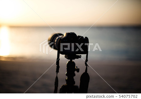 Digital camera on a tripod seashore to shoot sunse 54075702