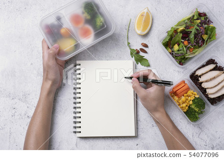 hands holding healthy lunch box and blank notebook 54077096