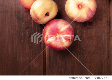 An overhead closeup photo of vibrant organic flat saturn peaches on a dark rustic wooden background An overhead closeup photo of vibrant organic flat saturn peaches on a dark rustic wooden background 54077660