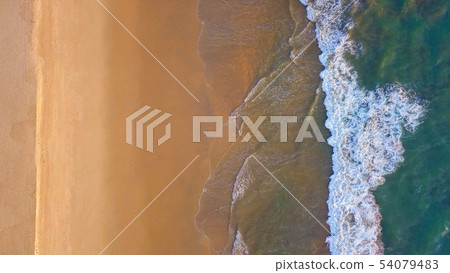 Aerial view of beach with waves rolling into the Aerial view of beach with waves rolling into the 54079483
