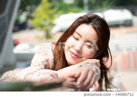 A woman smiling with two eyes closed up on a railing 54080712