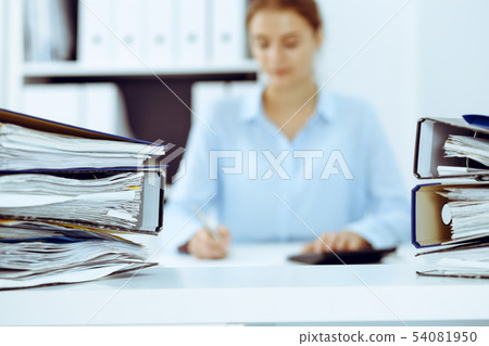 Binders with papers are waiting to be processed by business woman or bookkeeper back in blur 54081950