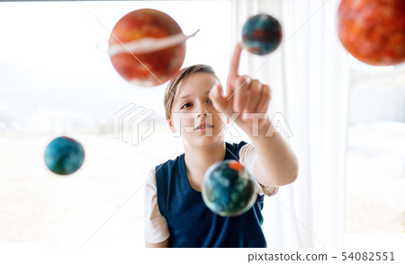 A small boy with model of solar system indoors. A small boy with model of solar system indoors. 54082551