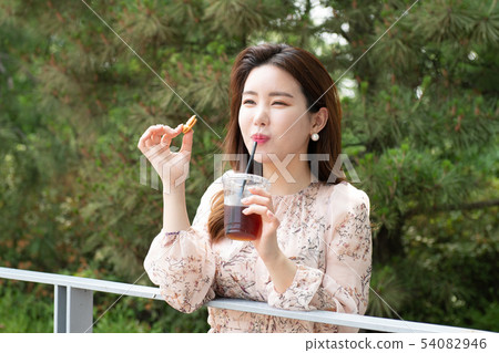 A woman who drinks coffee with sweets in the woods 54082946