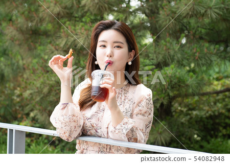 Long haired woman drinking coffee holding sweets in the woods 54082948