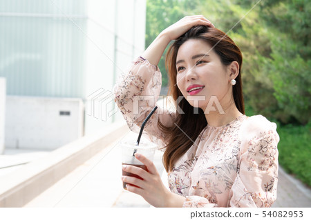 A woman who takes a break and takes a cup of coffee and sweeps her hair 54082953