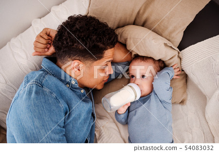 A top view of father and a son indoors at home, drinking milk from bottle. 54083032