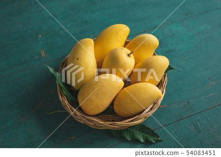 Yellow mango In the Yellow manbasket on green wood 54083451