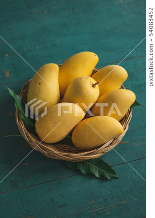 Yellow mango In the Yellow manbasket on green wood 54083452