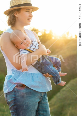 Mom with baby spending time together at sunset, on summer Mom with baby spending time together at sunset, on summer 54083603