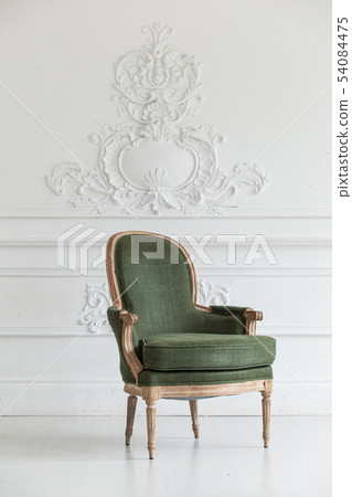 Living room in the Rococo style. Vintage green armchair against the wall with plaster stucco Living room in the Rococo style. Vintage green armchair against the wall with plaster stucco 54084475