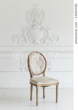 Living room in antique style. Vintage chair against the wall with a bas-relief of plaster stucco Living room in antique style. Vintage chair against the wall with a bas-relief of plaster stucco 54084486