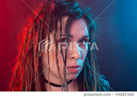 Youth, hairstyle and modern concept - young woman with dreadlocks over the red and blue light 54085160