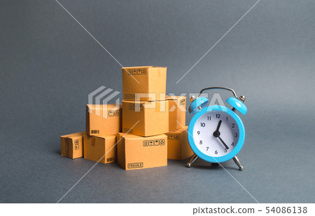 A stack of cardboard boxes and a blue alarm clock A stack of cardboard boxes and a blue alarm clock 54086138