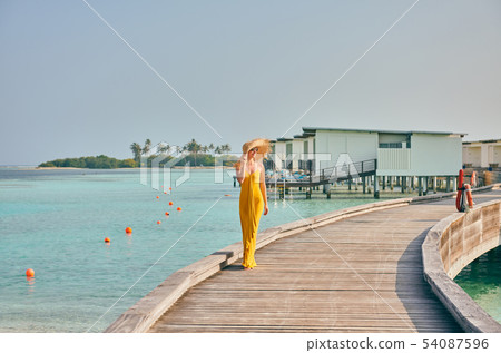 Woman in dress walking on tropical beach boardwalk Woman in dress walking on tropical beach boardwalk 54087596