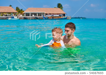 Toddler boy learns to swim with father 54087693