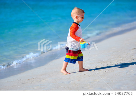 Two year old toddler playing on beach Two year old toddler playing on beach 54087765