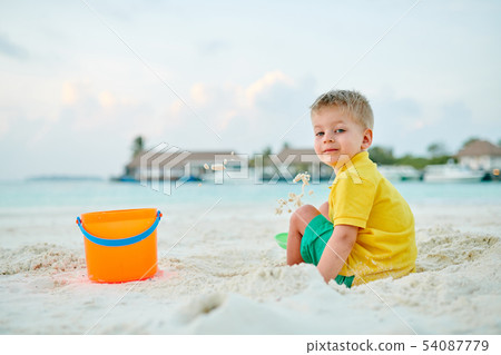 Three year old toddler playing on beach Three year old toddler playing on beach 54087779