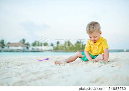 Three year old toddler playing on beach 54087780