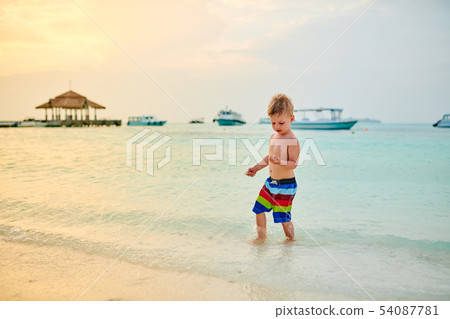 Three year old toddler boy on beach at sunset 54087781