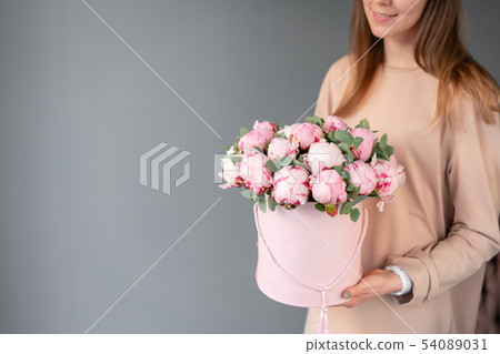 Pink peonies in pink round box. Beautiful peony flower in womans hands for catalog or online store 54089031