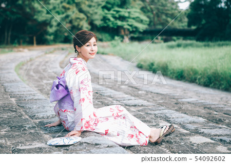 A woman in a yukata sitting on the banks of Kamogawa 54092602