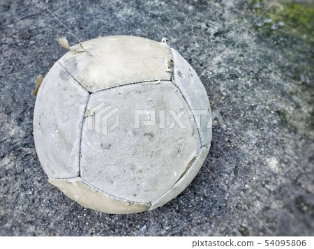 Old football lay down on playground floor. 54095806