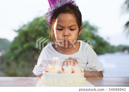 child celebrating birthday and blowing candles child celebrating birthday and blowing candles 54098942