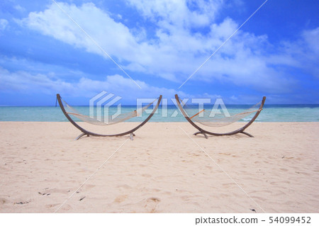 A pair of hammocks with blue sea and sky | Resort image Travel image A pair of hammocks with blue sea and sky | Resort image Travel image 54099452